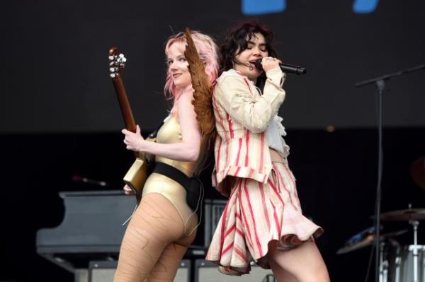 Emily Roberts (L) and Abigail Morris of The Last Dinner Party perform on stage. They stand back to back as Abigail sings and Emily plays guitar.
